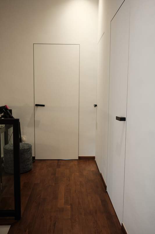 Hallway with white full-height wardrobe doors and a concealed door, timber flooring - Terrace house renovation with new facade and full interior (3TBA) | Larry Contractors, HDB Licensed Renovation Contractor, Singapore