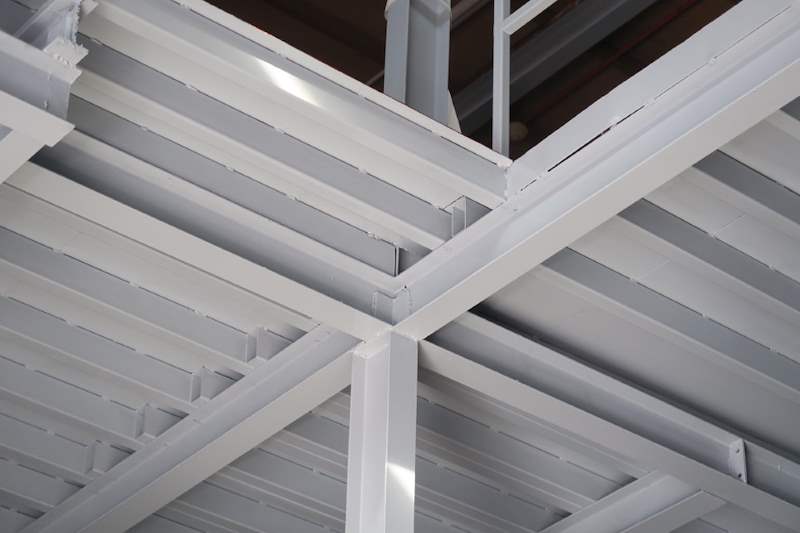 Underside of the steel mezzanine showing grey-painted I-beams and metal decking - Two-level steel mezzanine with staircases in an industrial unit (HF0107) | Larry Contractors, HDB Licensed Renovation Contractor, Singapore