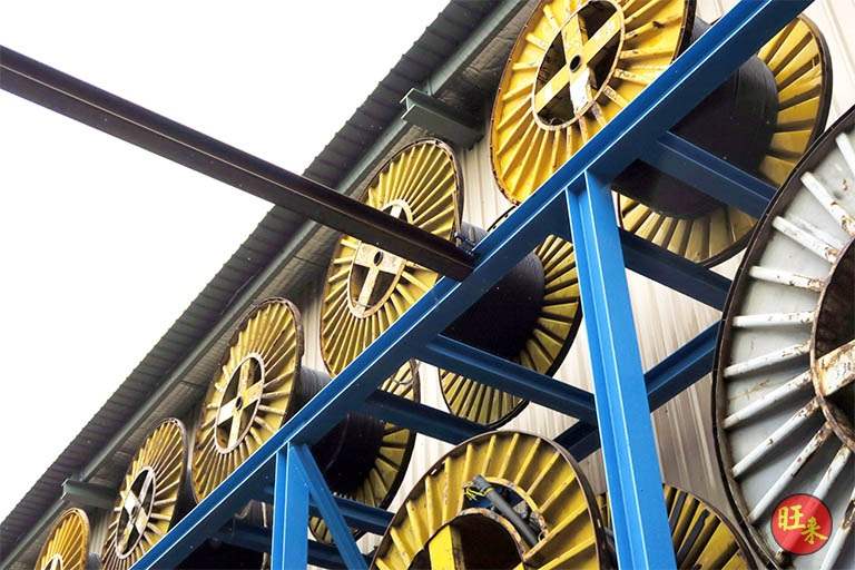 Looking up through the blue steel frames at drums stored on the upper tier - Heavy-duty cable drum racking in a cable yard (TSE) | Larry Contractors, HDB Licensed Renovation Contractor, Singapore