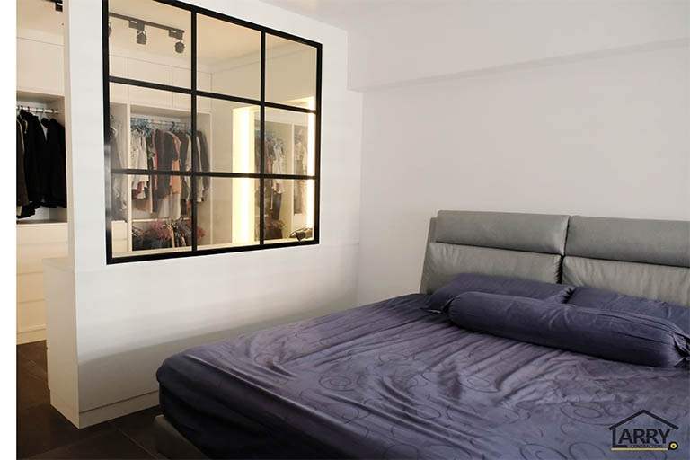 Black-framed glass wall separating the bedroom from the walk-in wardrobe with clothes hanging inside - HDB flat renovation with a blue kitchen and a glass-walled walk-in wardrobe (C18) | Larry Contractors, HDB Licensed Renovation Contractor, Singapore
