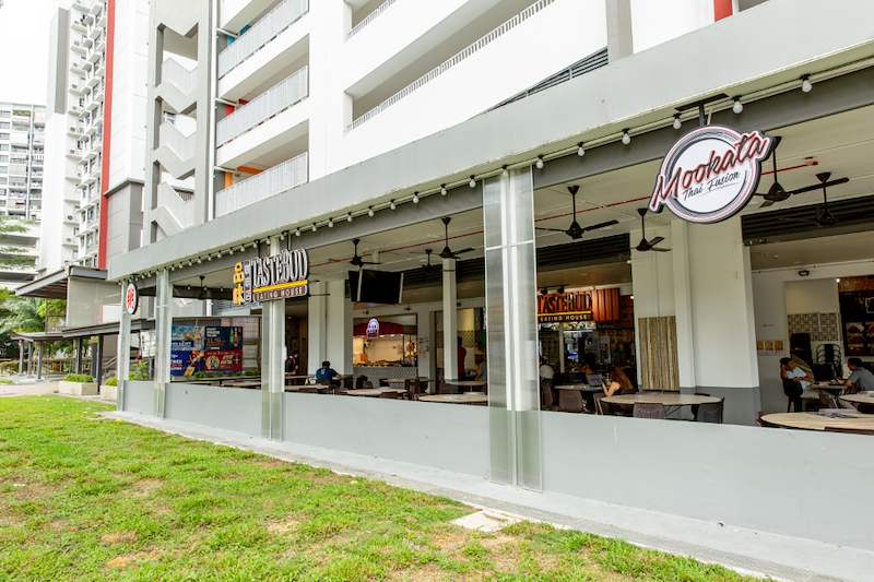 The finished extension along the lawn with the HDB block above and stall signage on the columns - Covered dining extension for a coffee shop under an HDB block (140CD) | Larry Contractors, HDB Licensed Renovation Contractor, Singapore