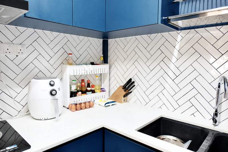 Kitchen worktop corner with the sink, air fryer and herringbone tile splashback - HDB flat renovation with a navy kitchen and a glass-walled walk-in wardrobe (407B) | Larry Contractors, HDB Licensed Renovation Contractor, Singapore