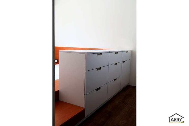 White chest of drawers built against the timber-laminate bedroom platform - HDB flat renovation with a platform bay window seat and blue kitchen (C20) | Larry Contractors, HDB Licensed Renovation Contractor, Singapore