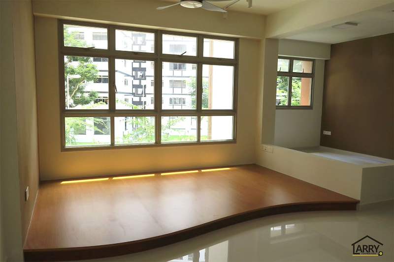 Curved timber-laminate platform running under the full-width living room windows - HDB flat renovation with a platform bay window seat and blue kitchen (C20) | Larry Contractors, HDB Licensed Renovation Contractor, Singapore