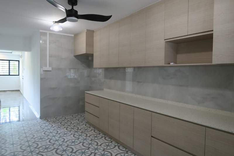 Kitchen with light wood cabinets, cream worktop, marble-look wall tiles and a ceiling fan - HDB kitchen, bathroom and service yard renovation (140PP) | Larry Contractors, HDB Licensed Renovation Contractor, Singapore