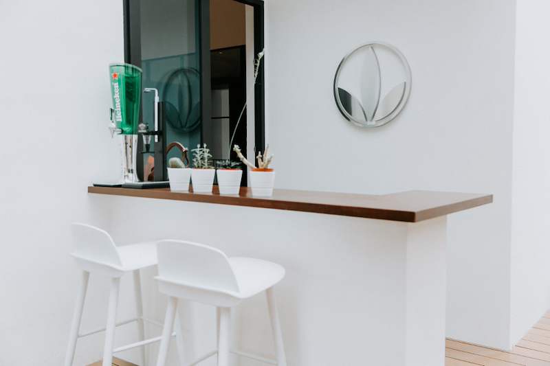 Outdoor bar counter with a timber worktop, two white bar stools and a wall-mounted beer tap - Landed house renovation with new facade, staircase and interiors (39EW) | Larry Contractors, HDB Licensed Renovation Contractor, Singapore