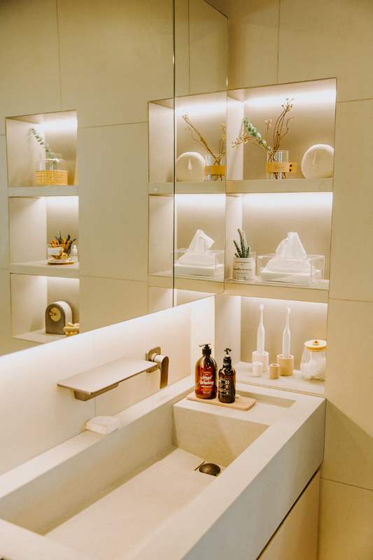Lit wall niches above a stone vanity basin with a brass tap - Full HDB maisonette renovation with a curved timber-slat island and lit staircase (140BB) | Larry Contractors, HDB Licensed Renovation Contractor, Singapore