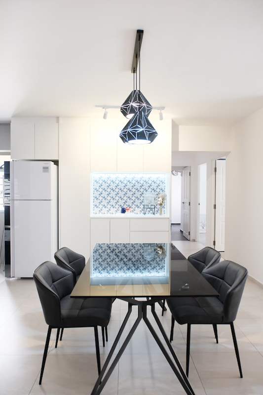 Dining table with black chairs under a geometric pendant, backlit tile niche and fridge beyond - HDB flat renovation with a navy kitchen and a glass-walled walk-in wardrobe (407B) | Larry Contractors, HDB Licensed Renovation Contractor, Singapore