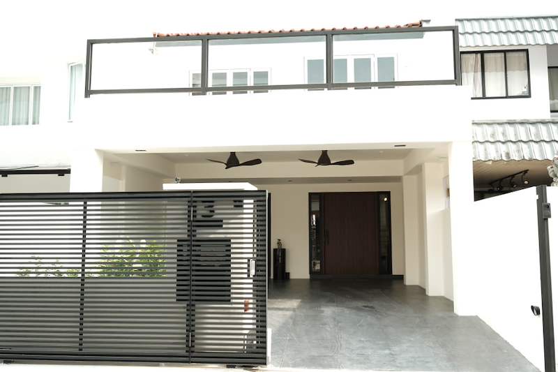 After: the new white facade with a horizontal-slat metal gate, ceiling fans in the porch and a glass balcony screen above - Terrace house renovation with new facade and full interior (3TBA) | Larry Contractors, HDB Licensed Renovation Contractor, Singapore
