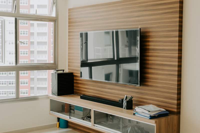 Timber-slat TV feature wall with a wall-mounted TV and a floating console with glass doors - HDB flat renovation with a glass-partitioned study, hidden shoe cabinet and navy kitchen (442BB) | Larry Contractors, HDB Licensed Renovation Contractor, Singapore