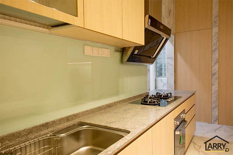 Kitchen worktop with the sink, gas hob and a pale green glass splashback - HDB flat renovation with full-height carpentry and a wood-tone kitchen (C12) | Larry Contractors, HDB Licensed Renovation Contractor, Singapore