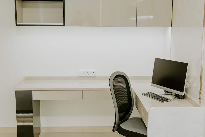 Built-in study desk with a monitor, office chair and overhead cabinets in cream high-gloss laminate - HDB flat renovation in cream and mirror-trim laminate with a galley kitchen (C10) | Larry Contractors, HDB Licensed Renovation Contractor, Singapore