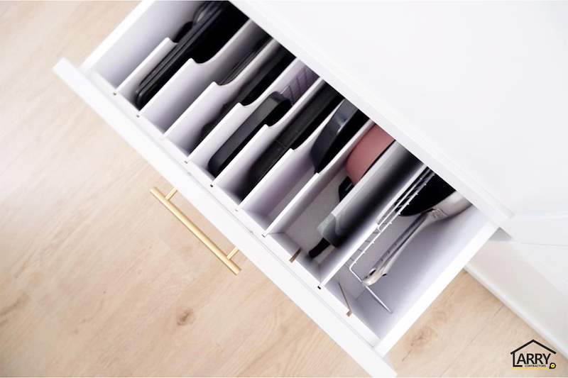 Pull-out kitchen drawer with vertical dividers holding trays and chopping boards, brass handle - HDB flat renovation in white shaker-style carpentry with brass handles (C05) | Larry Contractors, HDB Licensed Renovation Contractor, Singapore