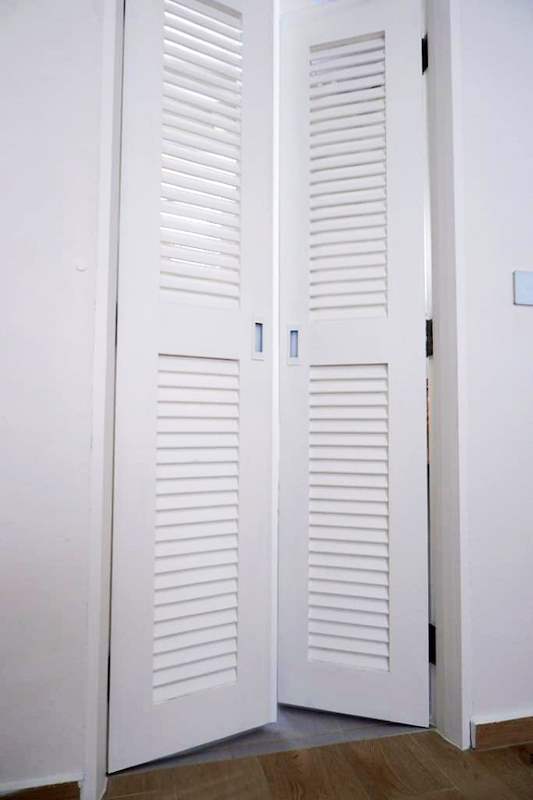 White louvred bi-fold cupboard doors in a hallway - HDB flat renovation in white shaker-style carpentry with brass handles (C05) | Larry Contractors, HDB Licensed Renovation Contractor, Singapore