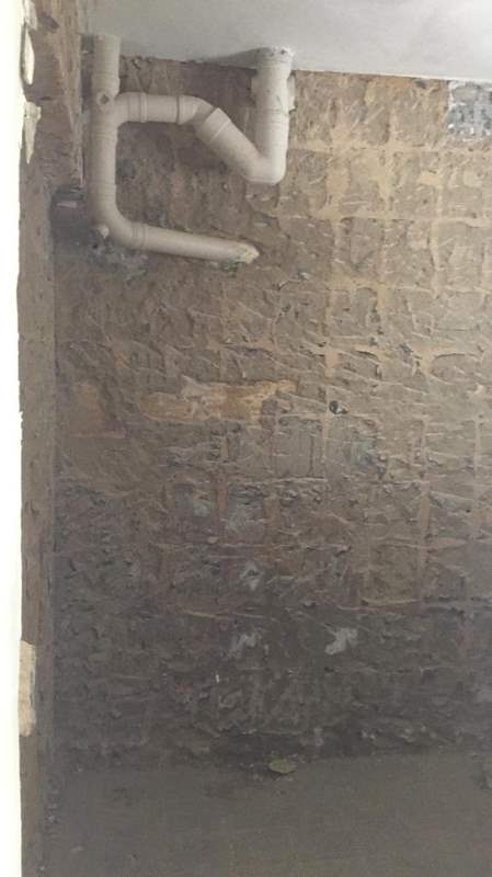 During works: a wall hacked back to bare brick with exposed pipework - HDB resale flat renovation with polished terrazzo floors, new kitchen and bathrooms (C04) | Larry Contractors, HDB Licensed Renovation Contractor, Singapore