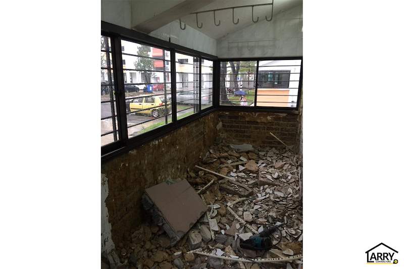 The laundry area stripped back to bare brick with rubble on the floor and corner windows - HDB resale flat renovation with polished terrazzo floors, new kitchen and bathrooms (C04) | Larry Contractors, HDB Licensed Renovation Contractor, Singapore