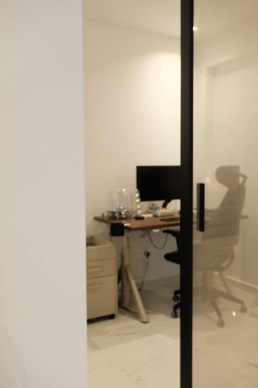 Home study behind a black-framed glass partition, with a desk, monitor and office chair - Terrace house renovation with new facade and full interior (3TBA) | Larry Contractors, HDB Licensed Renovation Contractor, Singapore