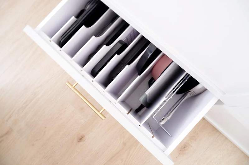 Pull-out kitchen drawer with vertical dividers holding trays and chopping boards, brass handle - HDB flat renovation in white shaker-style carpentry with brass handles (C05) | Larry Contractors, HDB Licensed Renovation Contractor, Singapore