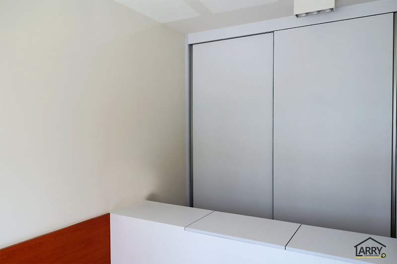 Bedroom with grey sliding-door wardrobes above a white built-in storage bench - HDB flat renovation with a platform bay window seat and blue kitchen (C20) | Larry Contractors, HDB Licensed Renovation Contractor, Singapore