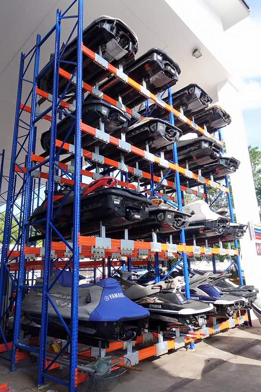 Five-tier steel rack of blue uprights and orange beams holding jet skis, inside a covered storage shed - Heavy-duty storage racking for boats and jet skis (Sentosa) | Larry Contractors, HDB Licensed Renovation Contractor, Singapore