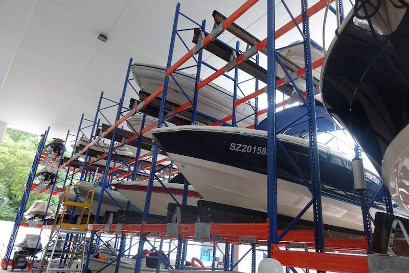 Boats on orange beams at the upper tiers of the rack, looking up between the blue uprights - Heavy-duty storage racking for boats and jet skis (Sentosa) | Larry Contractors, HDB Licensed Renovation Contractor, Singapore