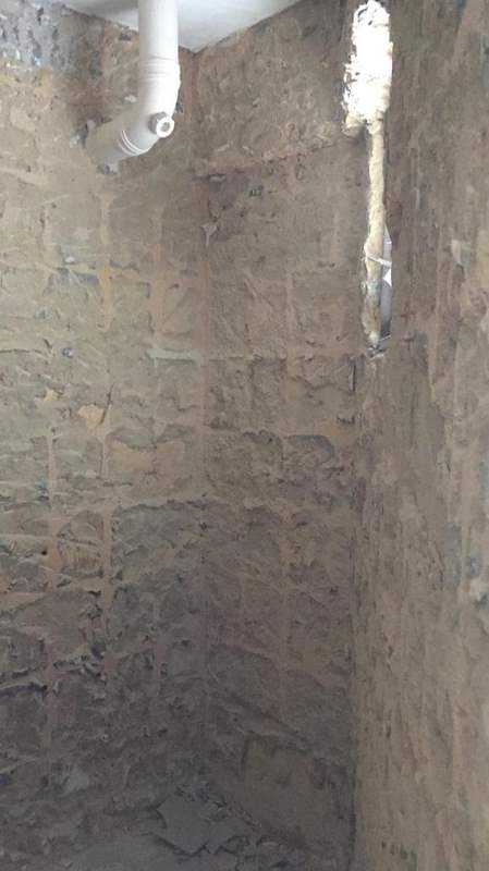 During works: a wall hacked back to brick with a pipe running down it - HDB resale flat renovation with polished terrazzo floors, new kitchen and bathrooms (C04) | Larry Contractors, HDB Licensed Renovation Contractor, Singapore