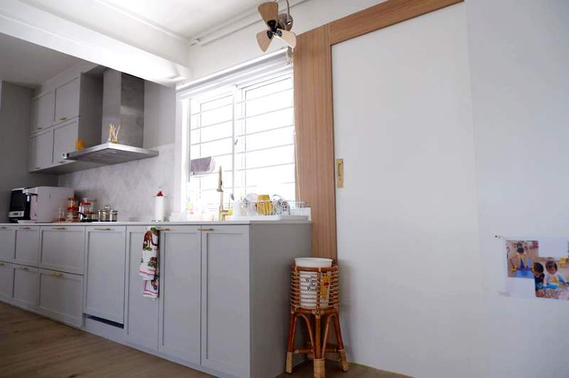White shaker kitchen run with brass handles, a cooker hood and a timber-framed doorway to the service yard - HDB flat renovation in white shaker-style carpentry with brass handles (C05) | Larry Contractors, HDB Licensed Renovation Contractor, Singapore