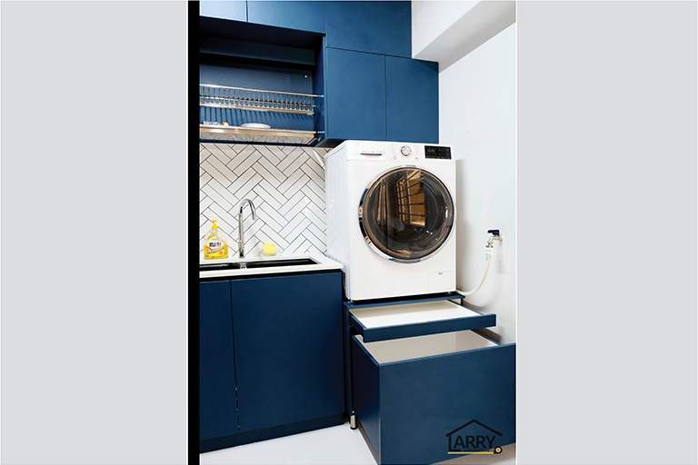 Kitchen corner with blue cabinets, a pull-out drawer and a washing machine on a raised base - HDB flat renovation with a blue kitchen and a glass-walled walk-in wardrobe (C18) | Larry Contractors, HDB Licensed Renovation Contractor, Singapore