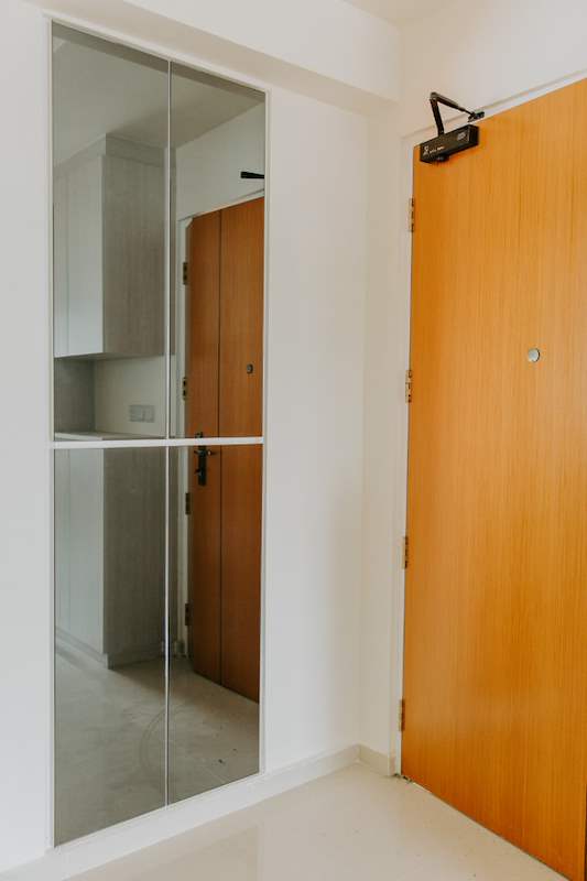 Mirrored panel beside the timber entrance door, viewed from inside - HDB flat renovation with a glass-partitioned study, hidden shoe cabinet and navy kitchen (442BB) | Larry Contractors, HDB Licensed Renovation Contractor, Singapore