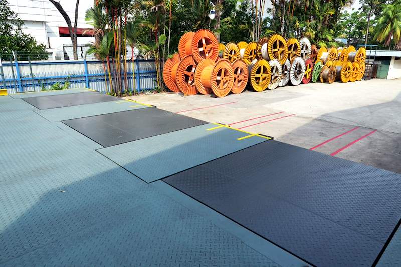 Checker-plate deck of the loading dock platform with cable drums stored in the yard beyond - Heavy-duty cable drum racking in a cable yard (TSE) | Larry Contractors, HDB Licensed Renovation Contractor, Singapore