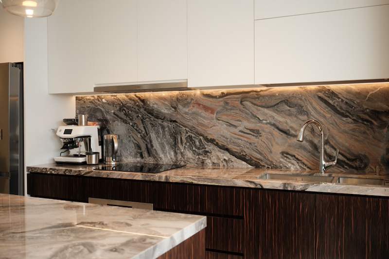 After: kitchen with white handleless upper cabinets, a veined stone splashback with under-cabinet lighting and dark wood-grain lower cabinets - Terrace house renovation with new facade and full interior (3TBA) | Larry Contractors, HDB Licensed Renovation Contractor, Singapore
