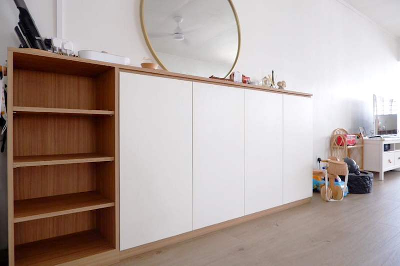 Long white sideboard with an oak top running along the living room wall, open oak shelves at one end - HDB flat renovation in white shaker-style carpentry with brass handles (C05) | Larry Contractors, HDB Licensed Renovation Contractor, Singapore