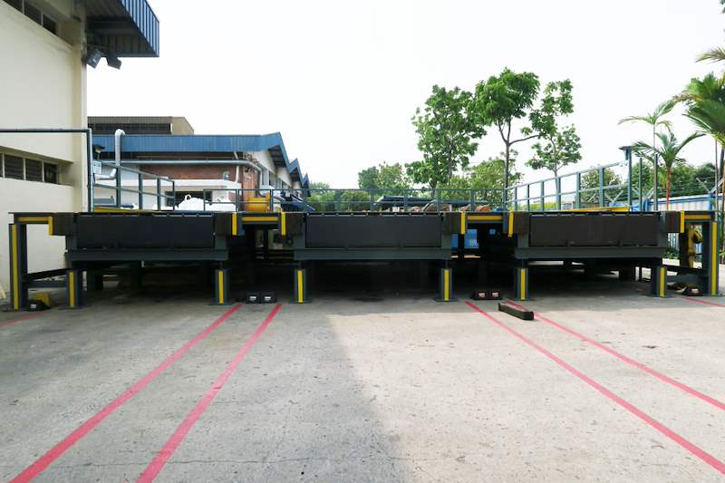 Row of steel dock platforms in the yard with cable drums and trees behind - Heavy-duty cable drum racking in a cable yard (TSE) | Larry Contractors, HDB Licensed Renovation Contractor, Singapore