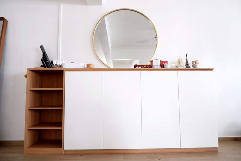 Low white sideboard with an oak top and open-shelf end, a round brass-framed mirror above - HDB flat renovation in white shaker-style carpentry with brass handles (C05) | Larry Contractors, HDB Licensed Renovation Contractor, Singapore