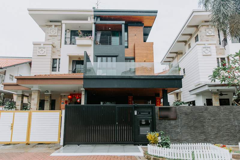 Front elevation after renovation - dark panelled and timber-clad facade, glass balcony screen and a black metal sliding gate - Landed house renovation with new facade, staircase and interiors (39EW) | Larry Contractors, HDB Licensed Renovation Contractor, Singapore