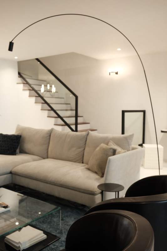 Living room with a beige sectional sofa, a black arc floor lamp and the staircase behind - Terrace house renovation with new facade and full interior (3TBA) | Larry Contractors, HDB Licensed Renovation Contractor, Singapore