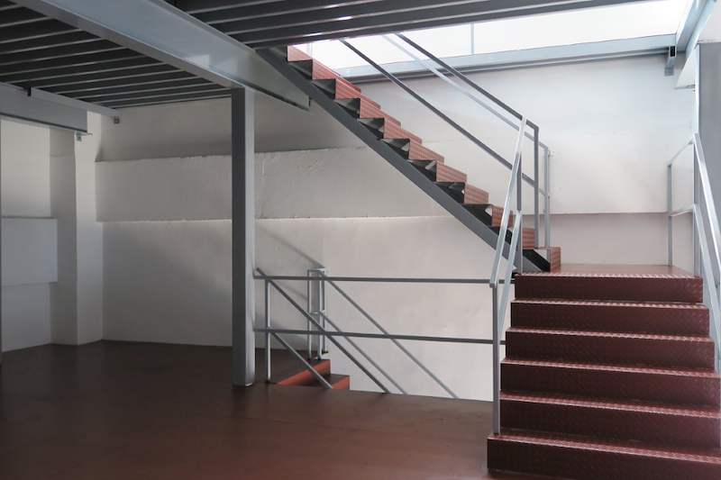 Steel staircase with red checker-plate treads rising to the mezzanine deck - Two-level steel mezzanine with staircases in an industrial unit (HF0107) | Larry Contractors, HDB Licensed Renovation Contractor, Singapore