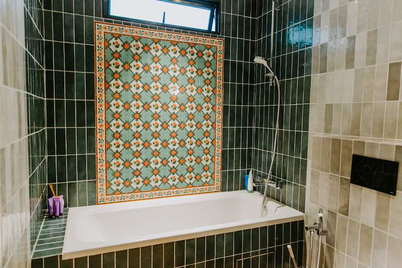 Bathroom with dark green wall tiles, a patterned tile feature panel over the built-in bath and a rain shower - Landed house renovation with new facade, staircase and interiors (39EW) | Larry Contractors, HDB Licensed Renovation Contractor, Singapore
