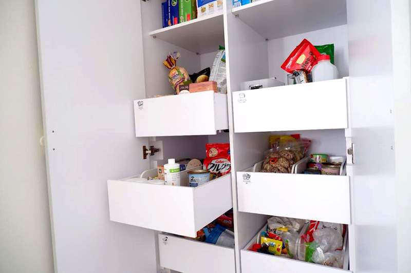 Close view of the pantry cabinet pull-out drawers loaded with packets and bottles - HDB flat renovation in white shaker-style carpentry with brass handles (C05) | Larry Contractors, HDB Licensed Renovation Contractor, Singapore