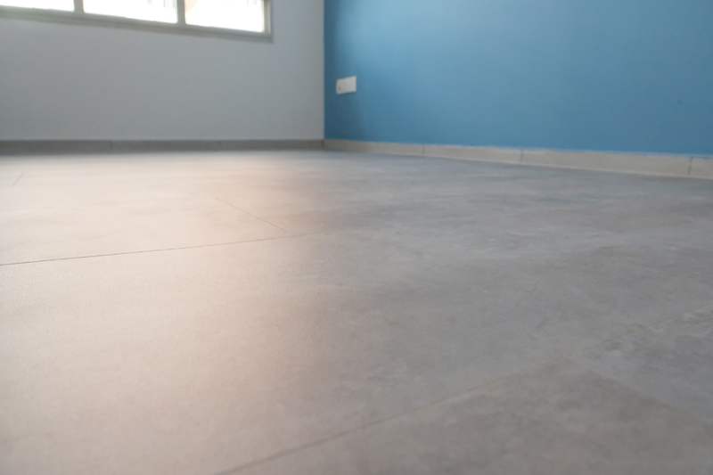 Empty room with a blue painted wall and large-format grey floor tiles - HDB flat renovation with a navy kitchen and a glass-walled walk-in wardrobe (407B) | Larry Contractors, HDB Licensed Renovation Contractor, Singapore