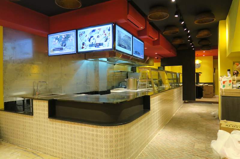 The finished open kitchen counter and menu screens with the dining area still being set up - Restaurant fit-out with an open kitchen counter and marble frontage (C48) | Larry Contractors, HDB Licensed Renovation Contractor, Singapore