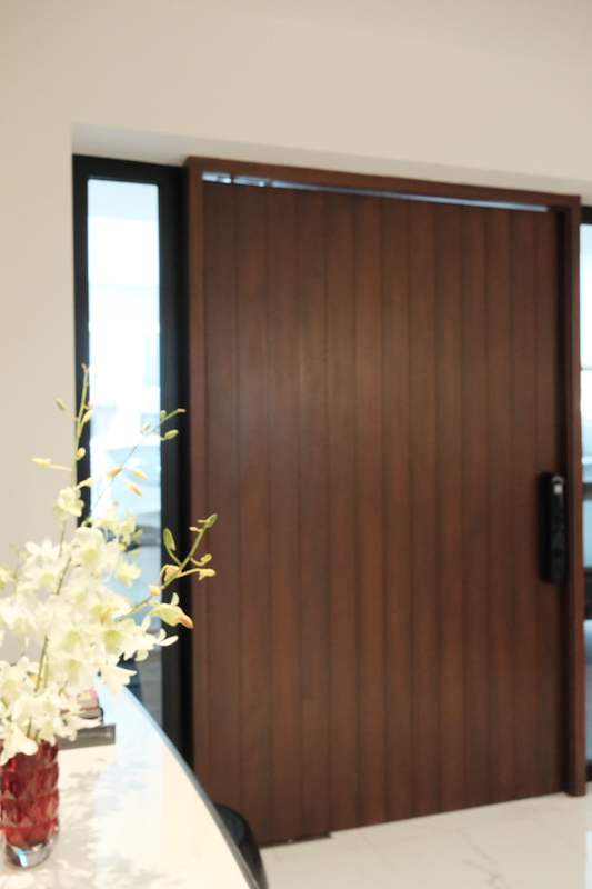 Dark timber pivot front door with a glass side panel and a black handle - Terrace house renovation with new facade and full interior (3TBA) | Larry Contractors, HDB Licensed Renovation Contractor, Singapore