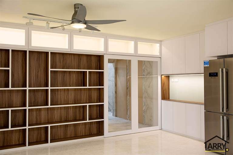 After: full-height white and walnut-look shelving partition beside the kitchen entrance, fridge alongside - HDB flat renovation with full-height carpentry and a wood-tone kitchen (C12) | Larry Contractors, HDB Licensed Renovation Contractor, Singapore