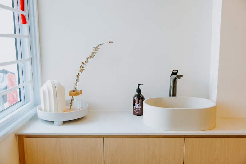 White countertop basin on a light oak vanity by the window - Full HDB maisonette renovation with a curved timber-slat island and lit staircase (140BB) | Larry Contractors, HDB Licensed Renovation Contractor, Singapore