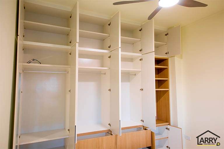 Bank of built-in wardrobes with the doors open, under a ceiling fan - HDB flat renovation with full-height carpentry and a wood-tone kitchen (C12) | Larry Contractors, HDB Licensed Renovation Contractor, Singapore