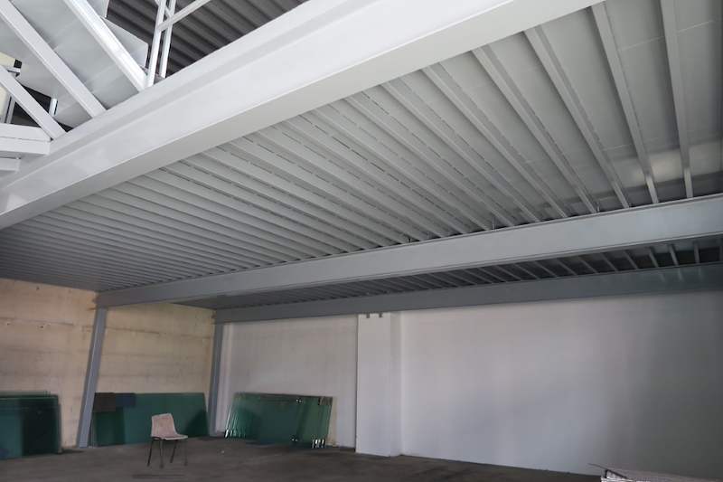 Steel mezzanine on grey I-beam columns with metal decking above an empty floor - Two-level steel mezzanine with staircases in an industrial unit (HF0107) | Larry Contractors, HDB Licensed Renovation Contractor, Singapore