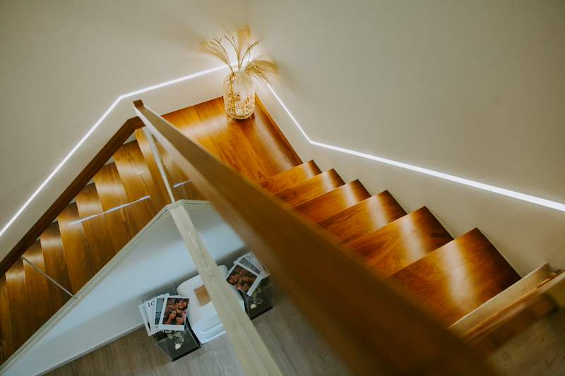 Looking down the timber staircase with a timber handrail and LED light line - Full HDB maisonette renovation with a curved timber-slat island and lit staircase (140BB) | Larry Contractors, HDB Licensed Renovation Contractor, Singapore