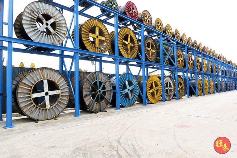 Two-tier outdoor racking loaded with drums of several colours, long view along the yard - Heavy-duty cable drum racking in a cable yard (TSE) | Larry Contractors, HDB Licensed Renovation Contractor, Singapore