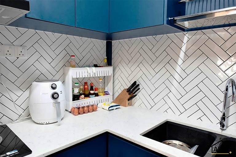 Kitchen worktop corner with the sink, herringbone splashback and blue cabinets - HDB flat renovation with a blue kitchen and a glass-walled walk-in wardrobe (C18) | Larry Contractors, HDB Licensed Renovation Contractor, Singapore
