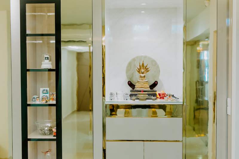 Lit altar niche with a marble-look back panel next to a black-framed glass display cabinet - HDB flat renovation in cream and mirror-trim laminate with a galley kitchen (C10) | Larry Contractors, HDB Licensed Renovation Contractor, Singapore